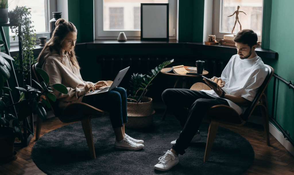 A man and woman sitting together using their electronic devices