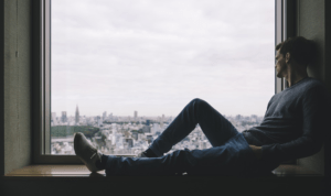 A man sitting and looking out of a window