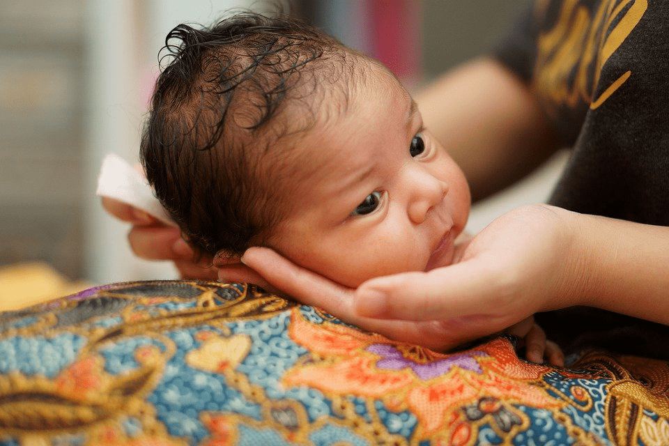 A mother holding the face of a newborn child
