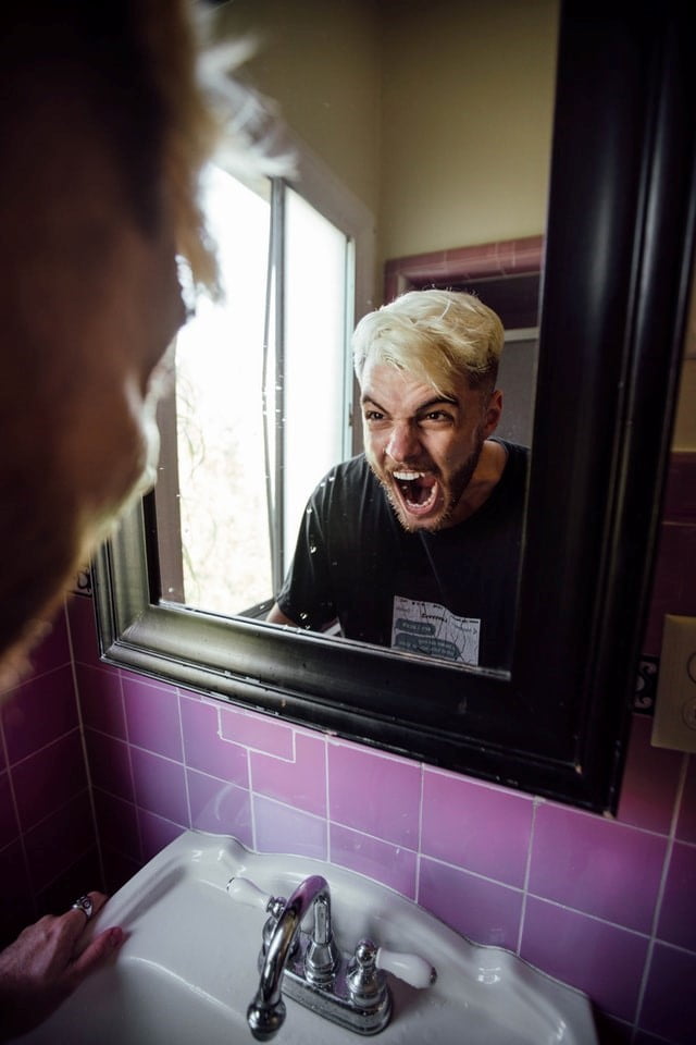 A man yells into a mirror