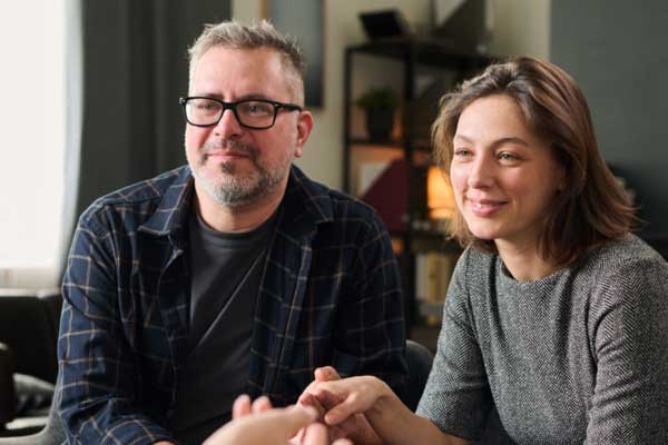 Smiling couple holding hands during therapy session
