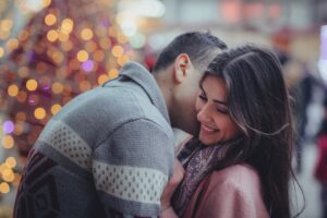 Couple embracing affectionately with soft lights in the background, representing emotional intimacy.