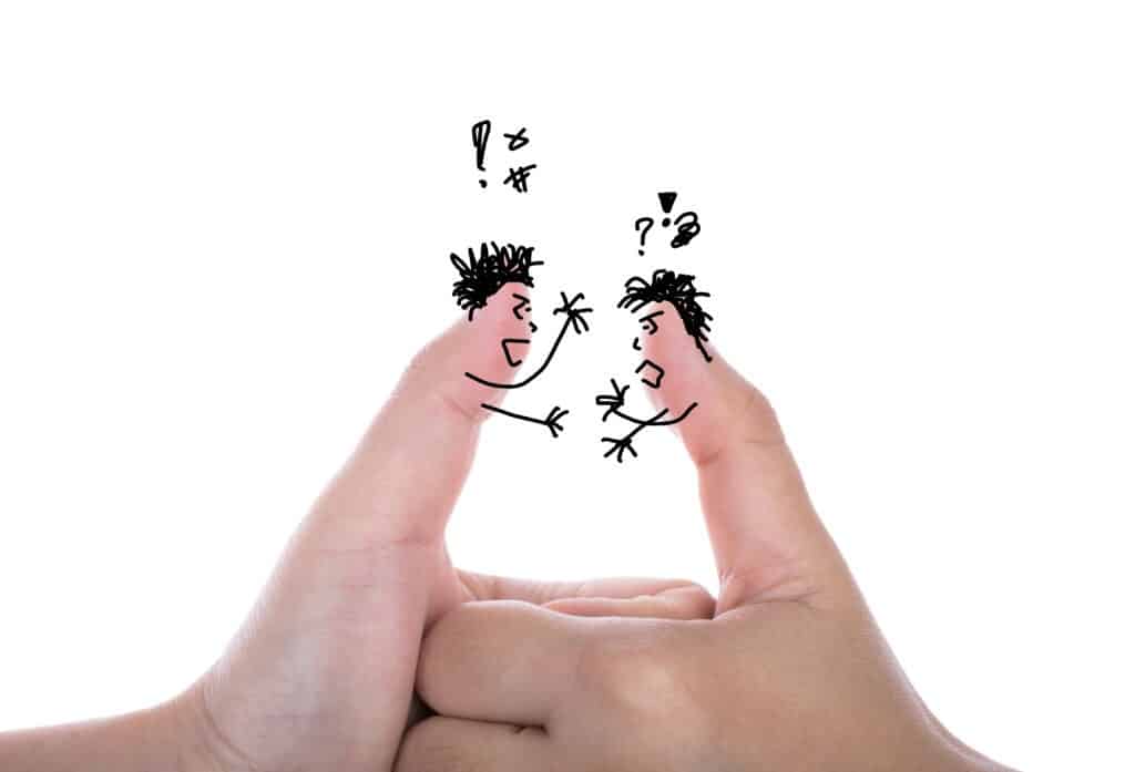 Cartoon couple drawn on thumbs arguing with symbols above their heads, representing emotional conflict in a marriage